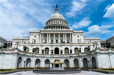 [ai] The United States Capitol building, featuring its iconic dome and neoclassical architecture, surrounded by a fountain and landscaped grounds under a blue sky with white clouds.
